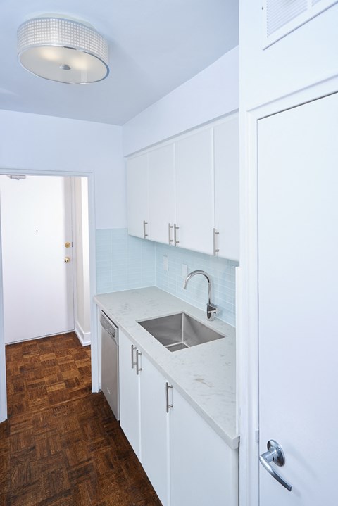 an empty kitchen with white cabinets and a sink